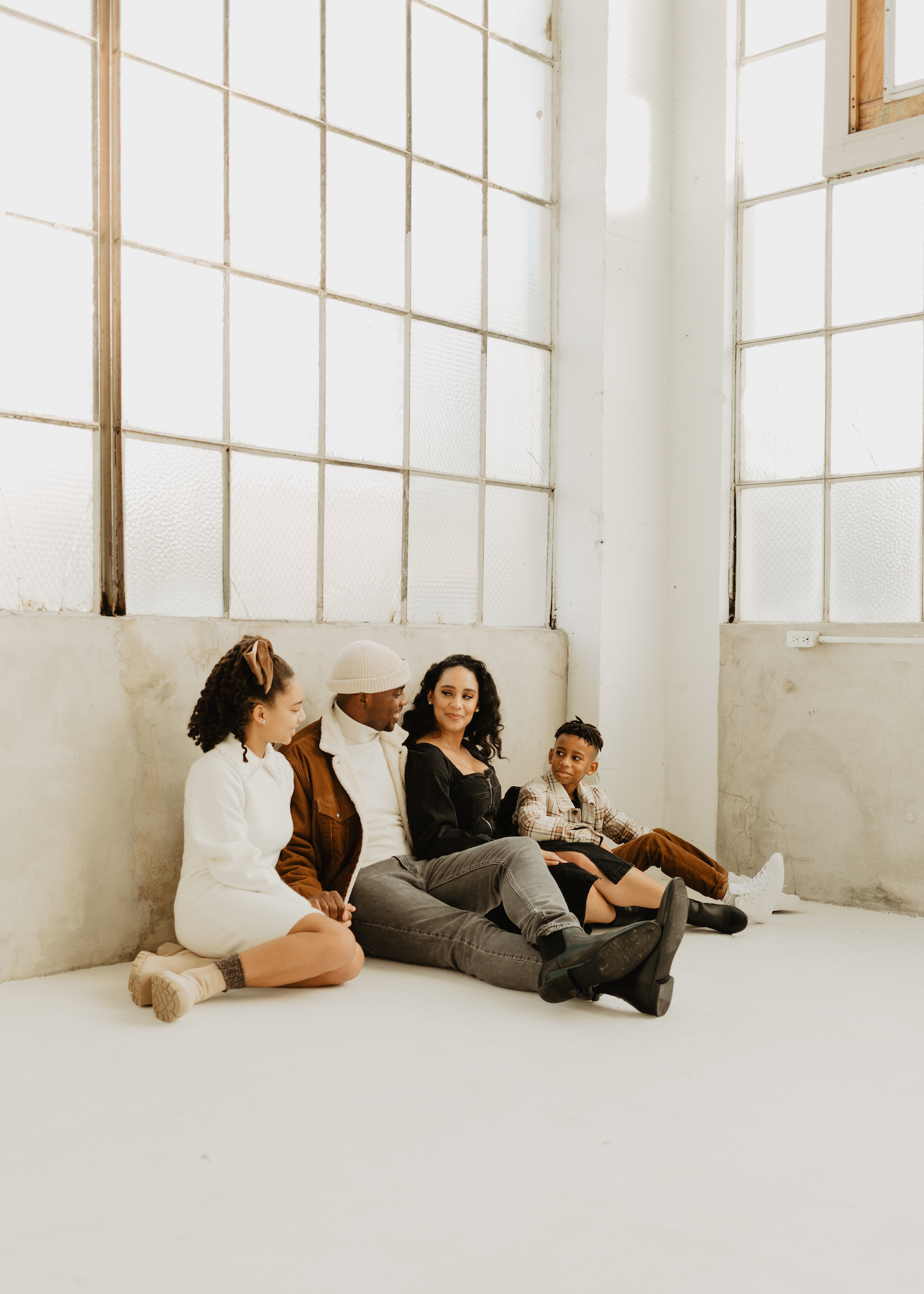 Family portrait beneath tall sunlit studio windows